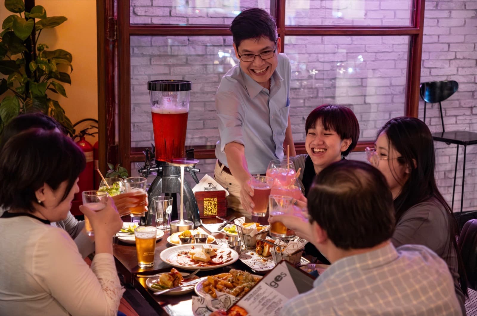 Friends toasting at a table in the 7 Bridges taproom