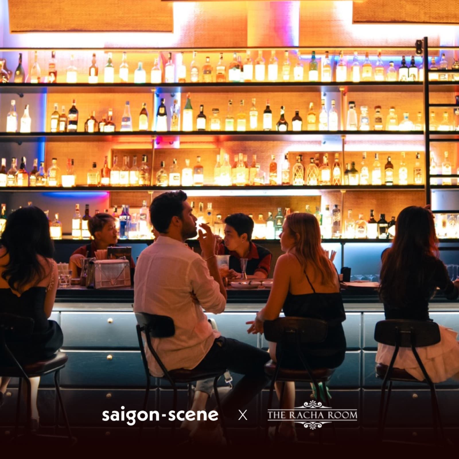 People on stools at The Racha Room's backlit bar