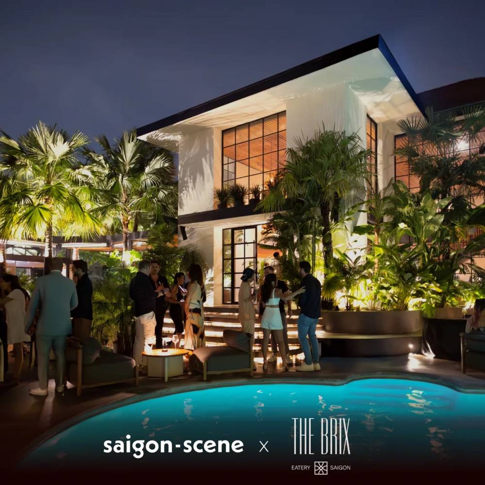 The pool at The Brix at night, with people on the lit terrace behind it